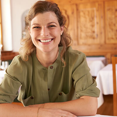 Eine Frau lächelt an einem Tisch im Gasthof.