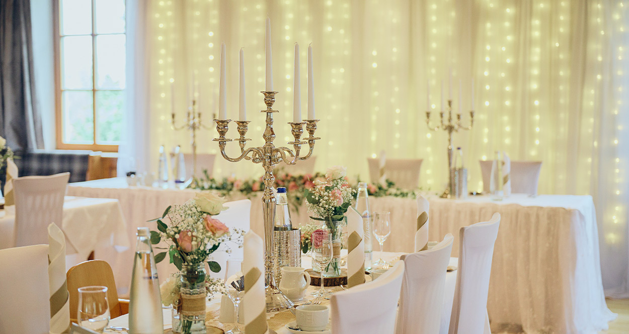 Eine feierliche Hochzeitsfeier mit weißen Tischdecken und Kerzen.