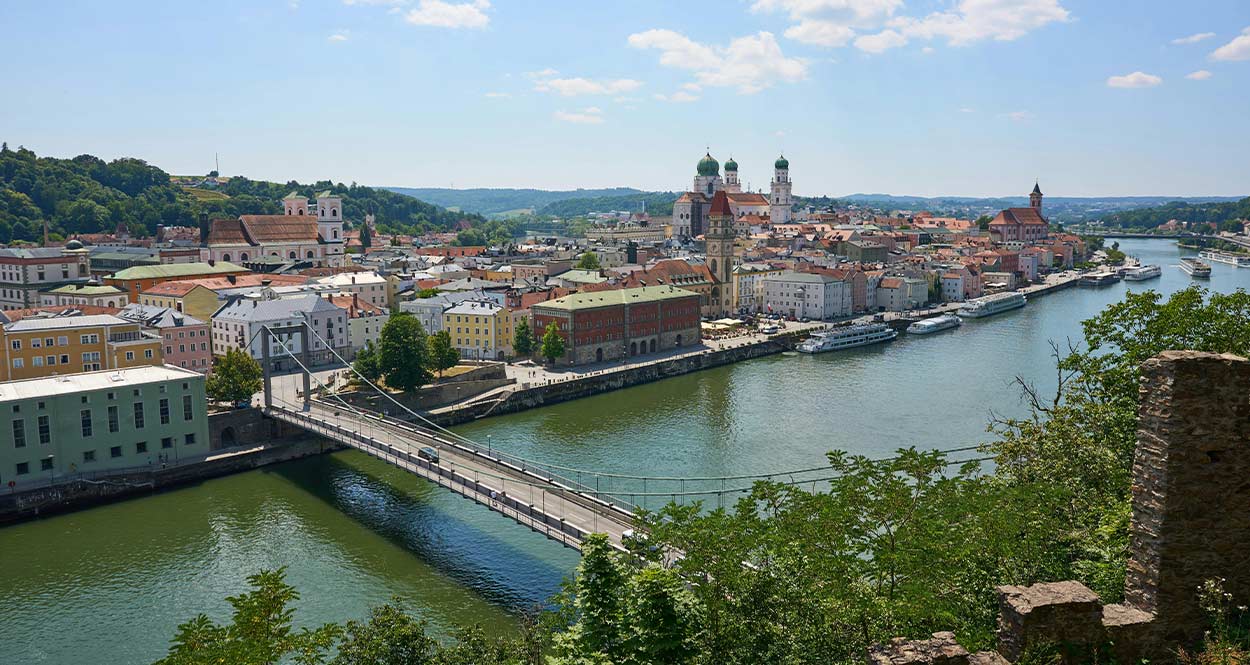 Blick auf die Stadt Passau mit Brücke über einen Fluss, die Touristen reizvolle Freizeitaktivitäten bietet.
