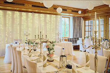 Eine Hochzeitsfeier, die mit weißen Tischdecken und Lichtern dekoriert ist.