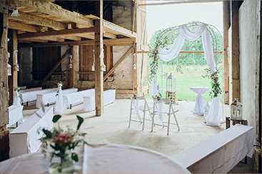 Eine Hochzeit in einer Scheune mit Blumen und Bänken