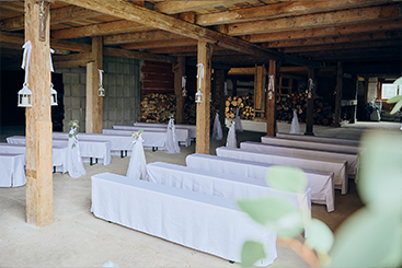Eine Hochzeitsfeier mit Tischen und Stühlen in einer Scheune.