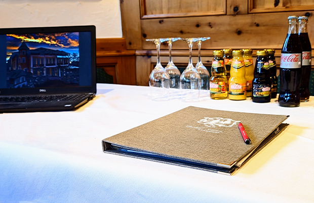 Ein Laptop, Arbeitsmappe, Flaschen und Gläser auf einem Tisch.