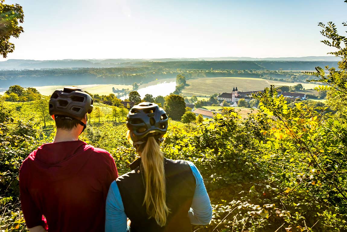 Zwei Fahrradfahre genießen ihre Freizeit mit Blick auf ein Tal.