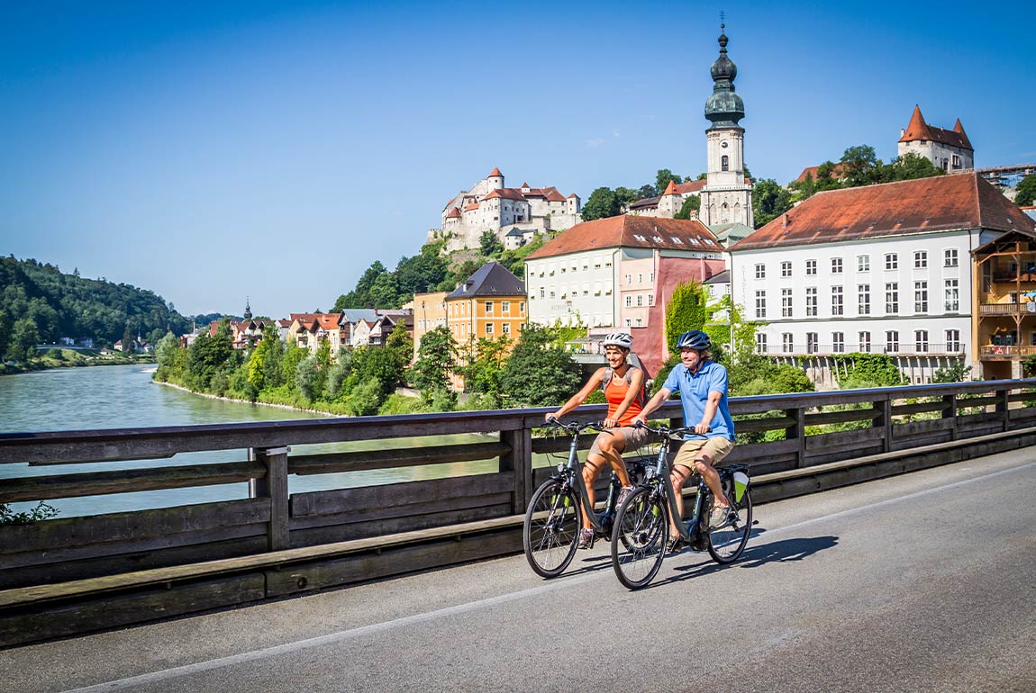 Zwei Menschen genießen ihre Freizeit beim Fahrradfahren auf einer Brücke über einem Fluss.