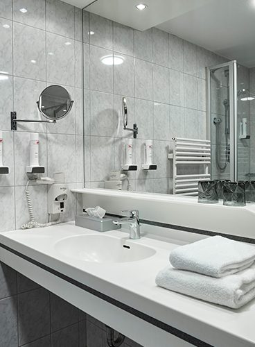 Ein Badezimmer mit Waschbecken und Spiegel, das Impressionen ausstrahlt.