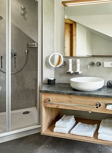 Ein Badezimmer mit Waschbecken und Dusche, eleganter Ausstattung und ruhiger Ästhetik.